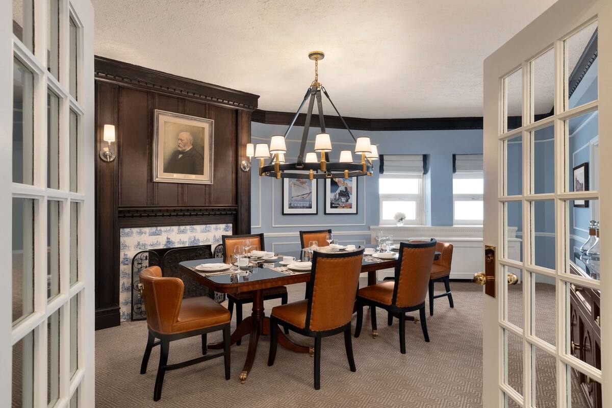 A dining room with a wooden table set for six, surrounded by upholstered chairs.