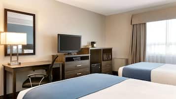Habitación de hotel con dos camas, un escritorio con televisor, una silla, lámpara de escritorio, microondas y minibar.