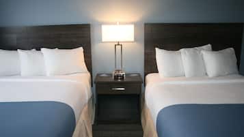 Une chambre d’hôtel avec deux lits, une table de chevet avec une lampe et une petite table avec une horloge.