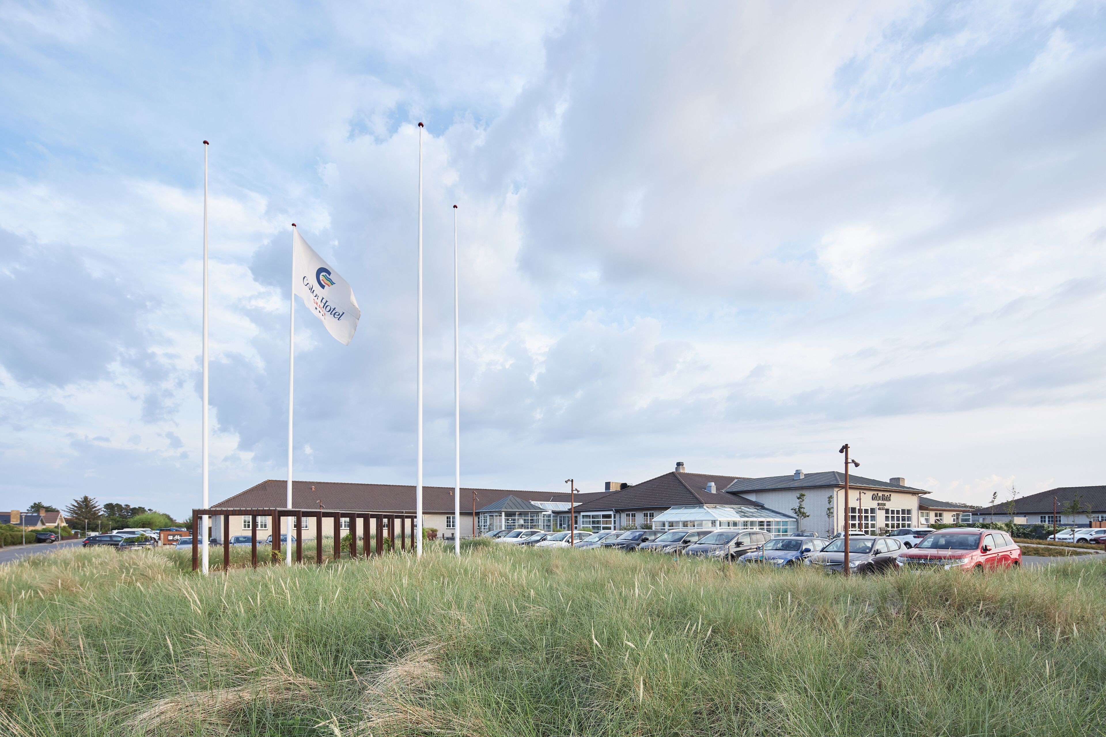 A hotel with a parking lot, a covered outdoor area, and a flag.