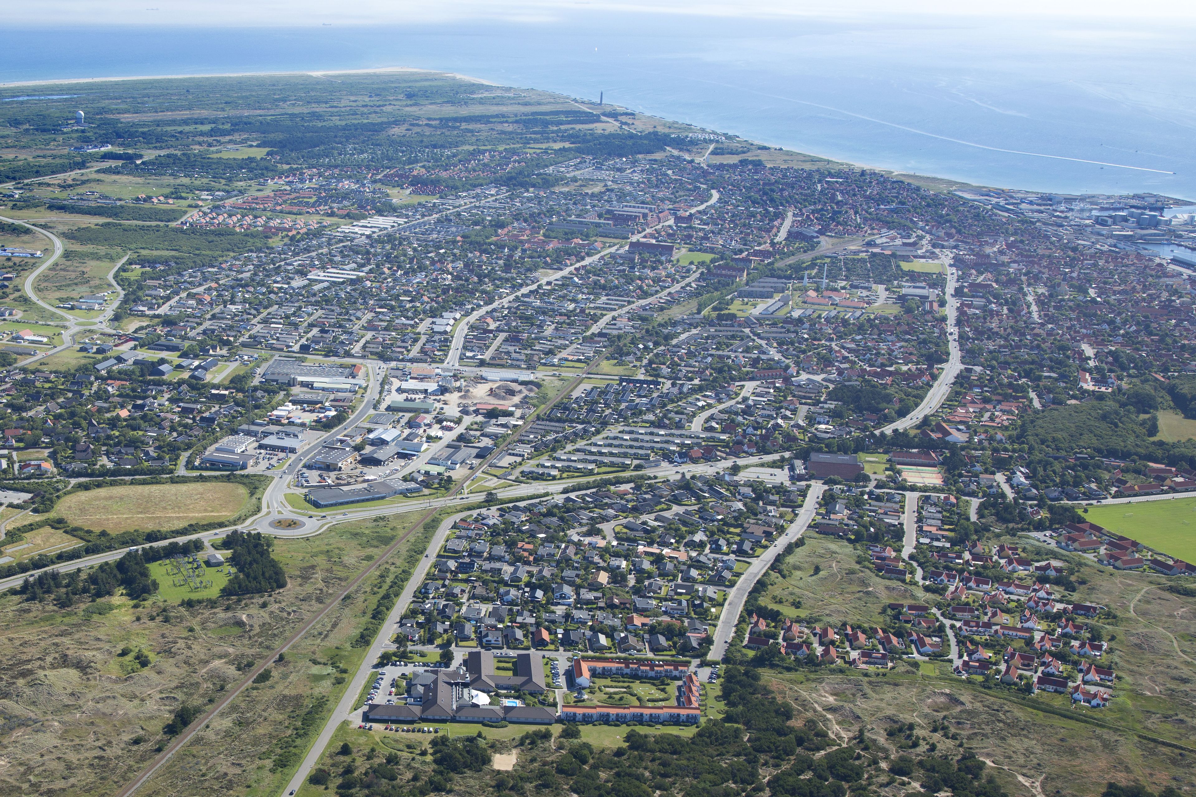 An aerial view of a residential area with houses, roads, and a large industrial complex.