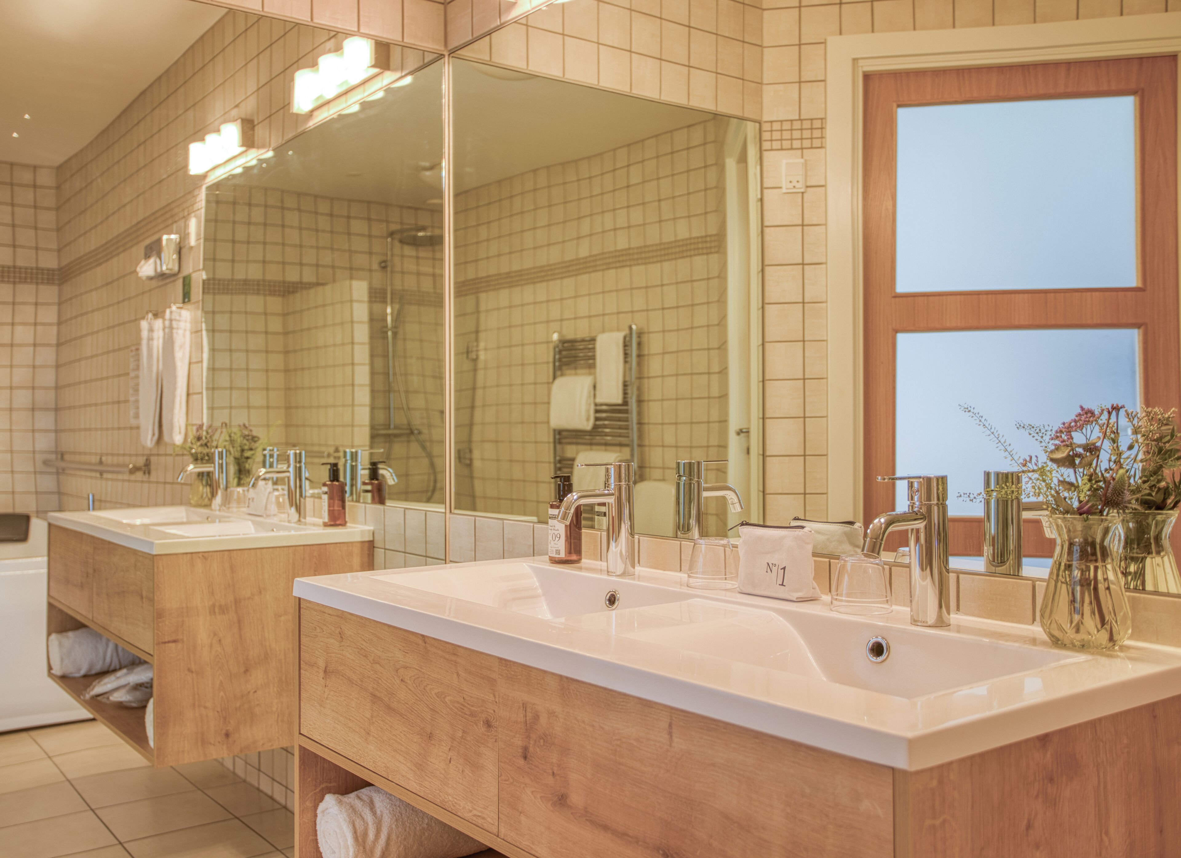 Un baño moderno con dos lavamanos, un espejo grande y un mueble de tocador de madera.