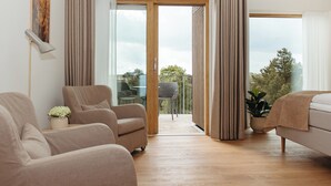 A modern living room with a sofa, a chair, and a table. There is a balcony with a chair and a plant. - Color Hotel Skagen (Skagen)
