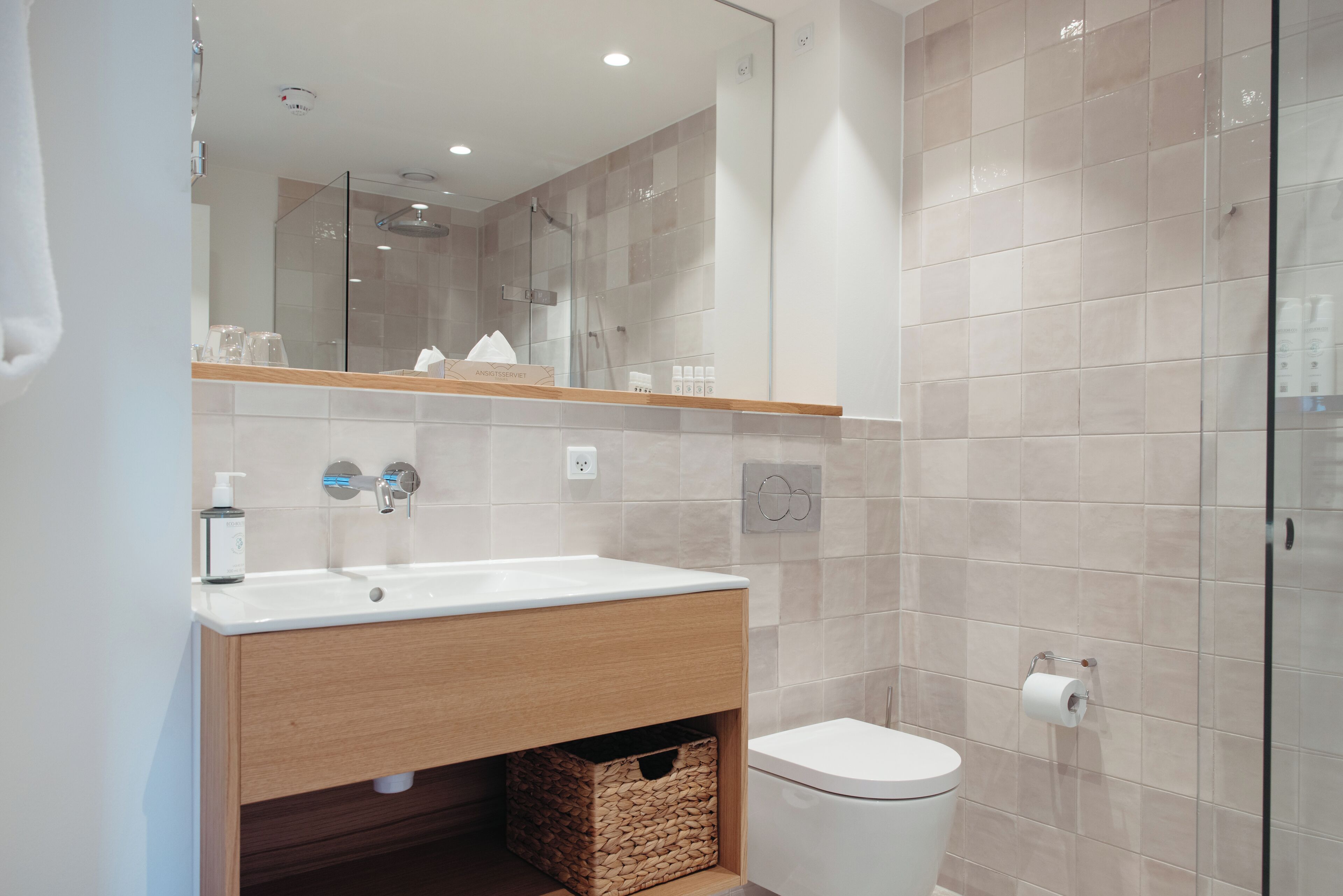 A modern bathroom with a wooden vanity, a white sink, and a toilet.