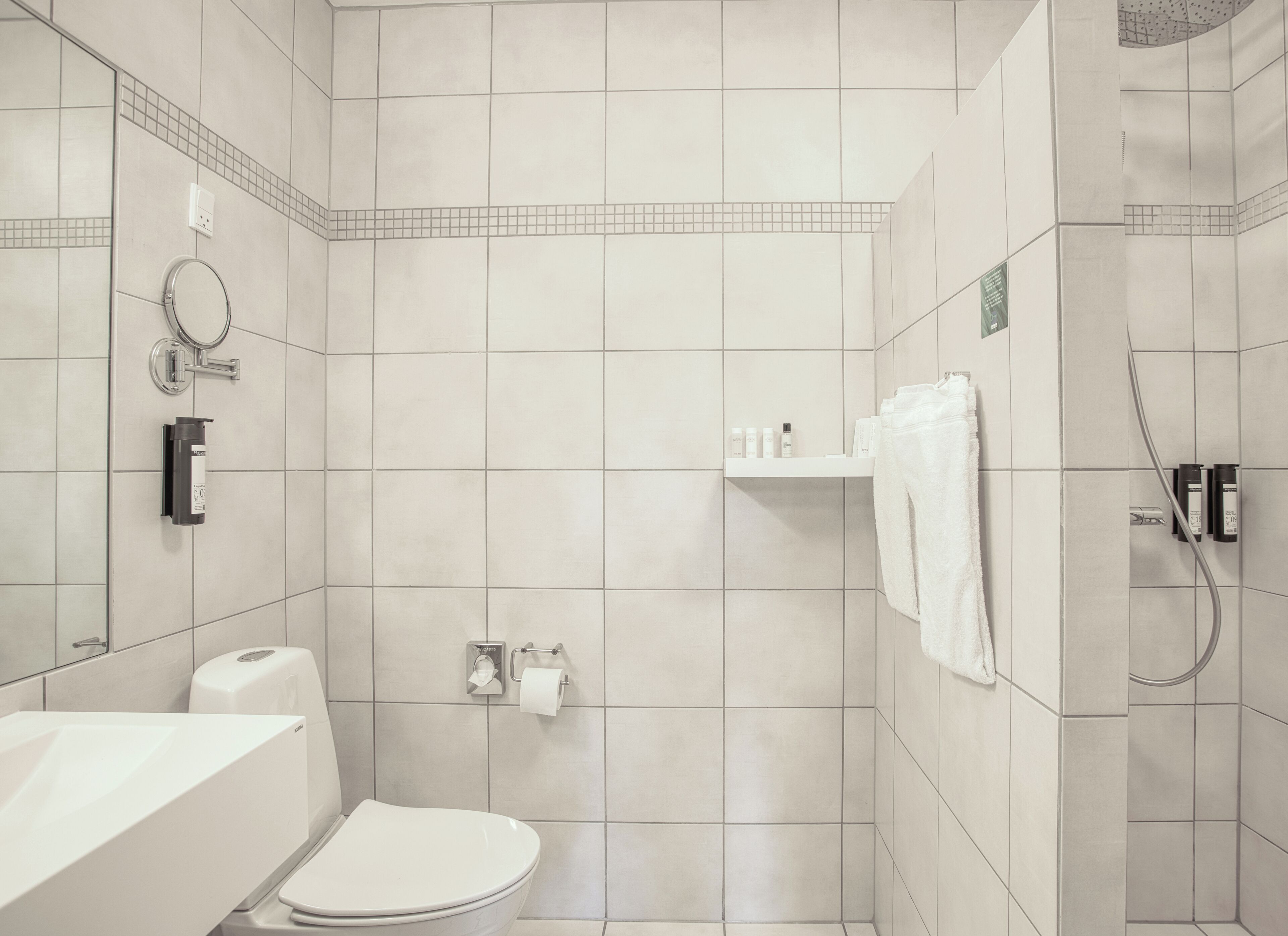 Een badkamer met toilet, wastafel, spiegel en douche.
