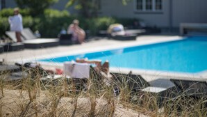 A swimming pool with lounge chairs and a house in the background. - Color Hotel Skagen (Skagen)
