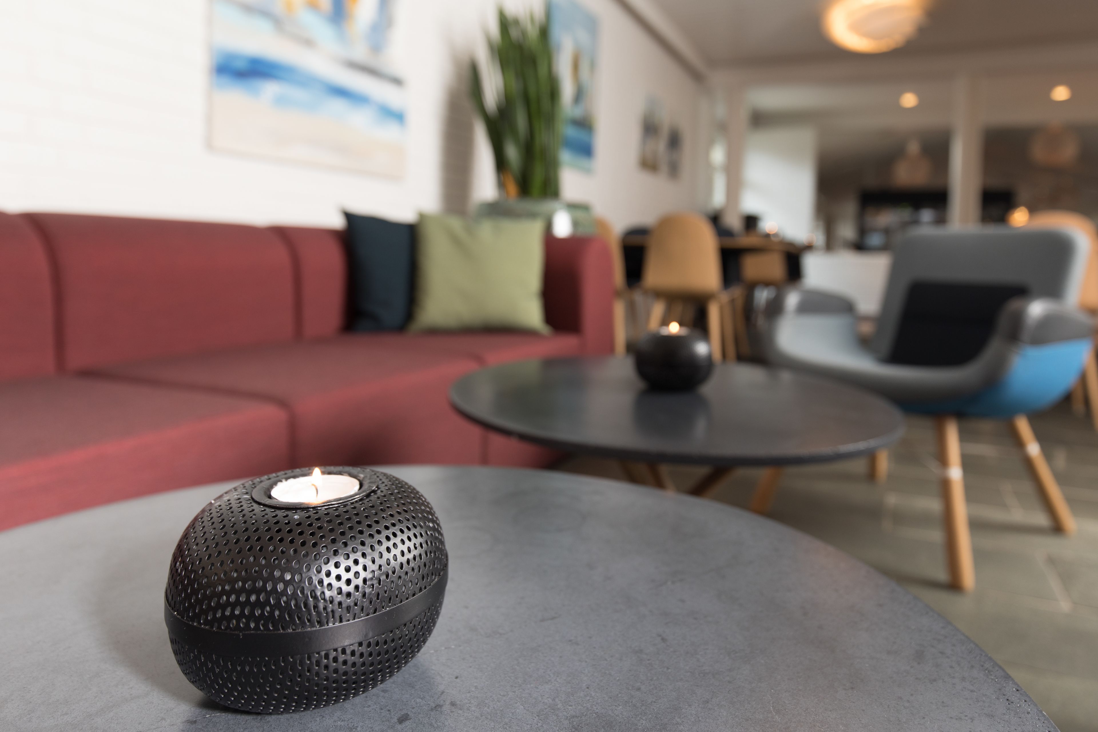 Una sala moderna con una mesa redonda, un sofá rojo y un altavoz decorativo.