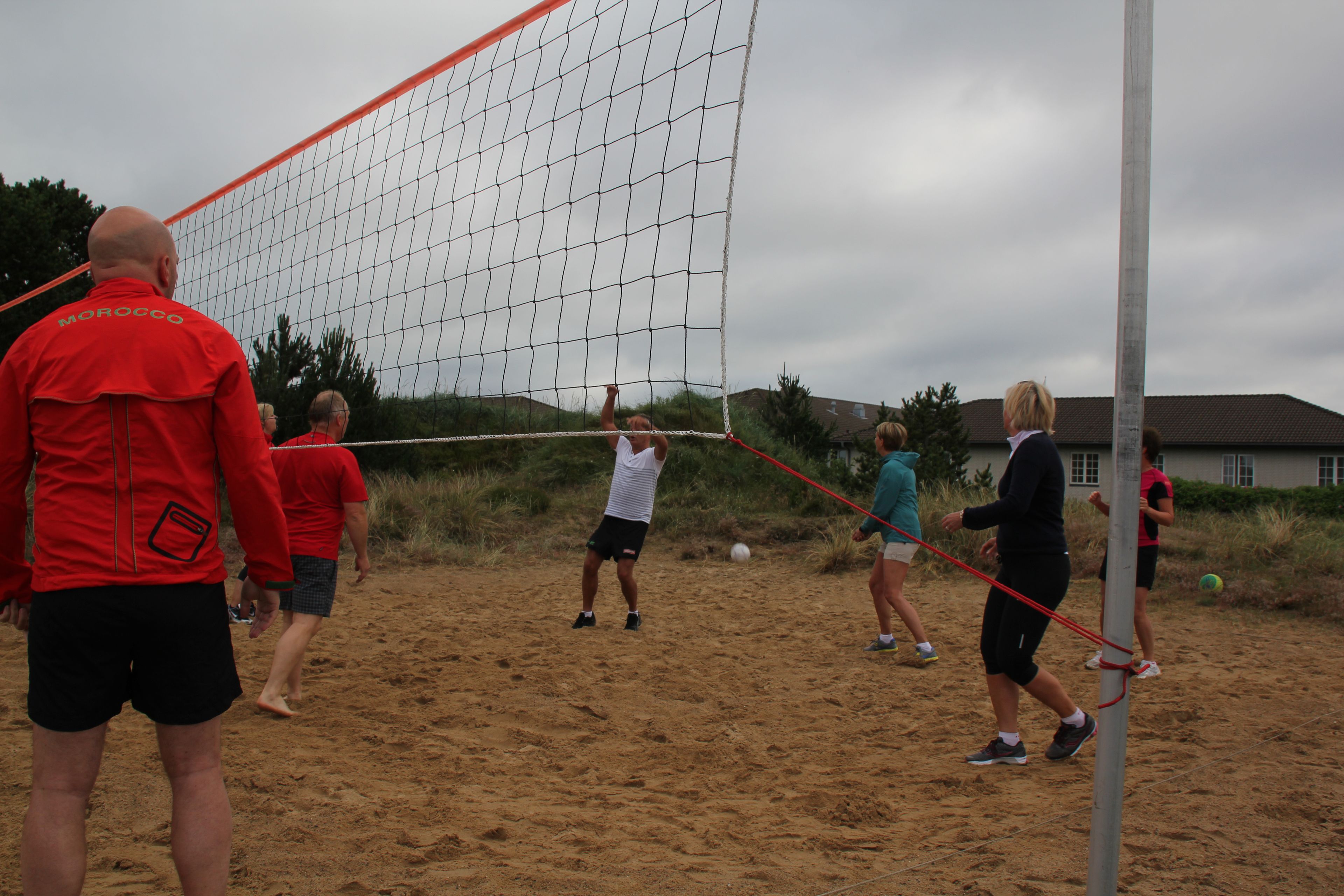 A group of people playing volleyball on a sandy beach.