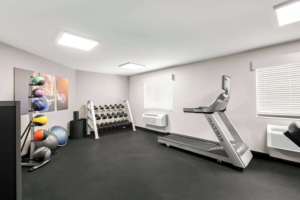 A gym with a treadmill, exercise balls, and dumbbells.