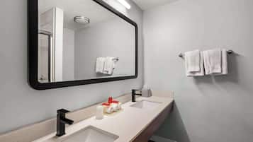 Een moderne badkamer met een grote spiegel, twee wastafels en een handdoekhouder.