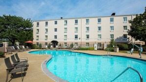 Une piscine avec des chaises longues et un bâtiment en arrière-plan.