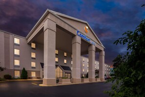 A hotel with a prominent sign, large columns, and a parking lot. - Comfort Inn St. Louis - Westport Event Center (Maryland Heights)