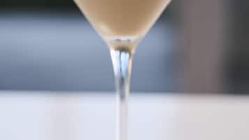 A martini glass with a creamy drink on a white surface.