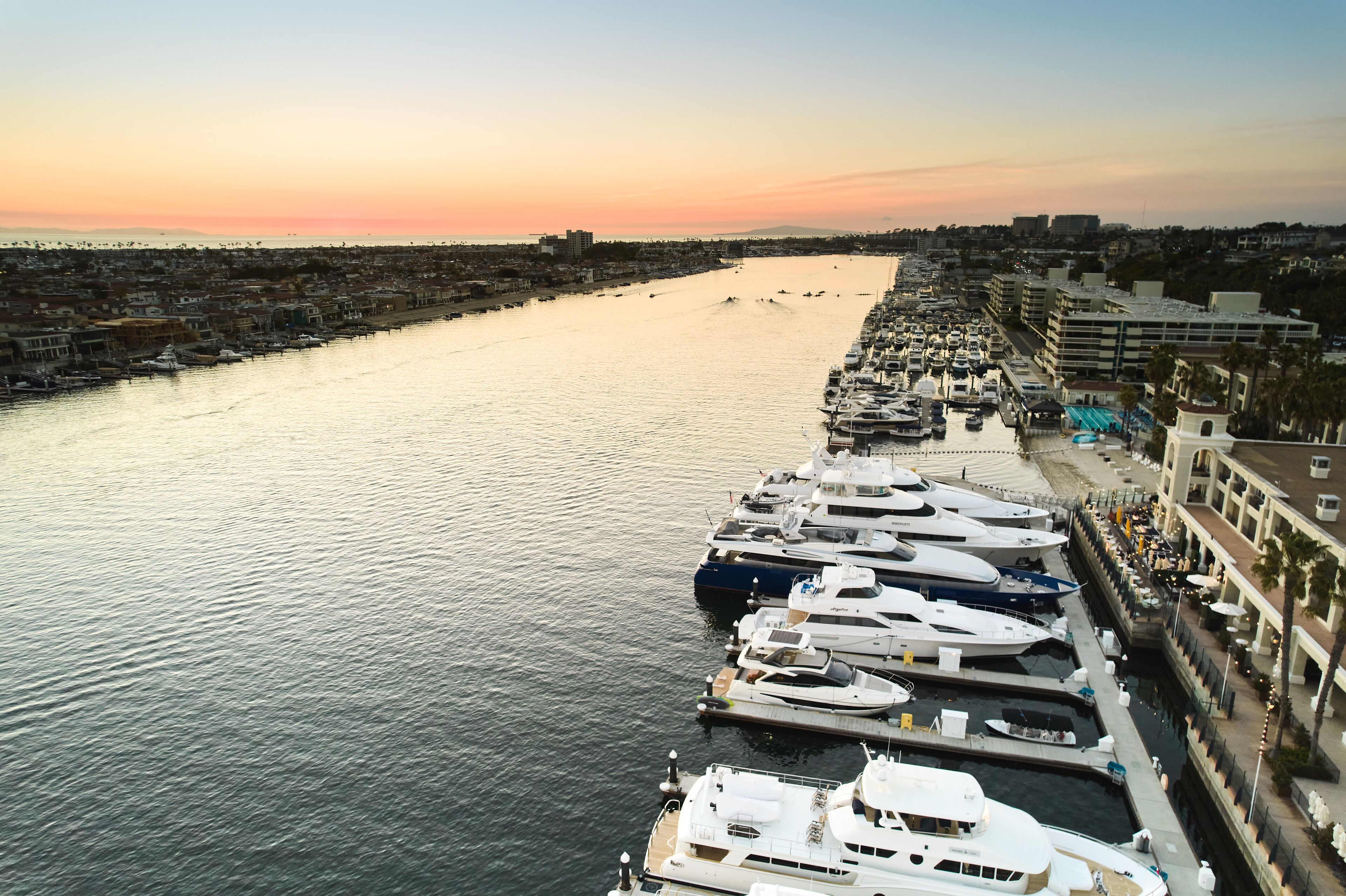 A marina with multiple yachts docked along a waterfront promenade.