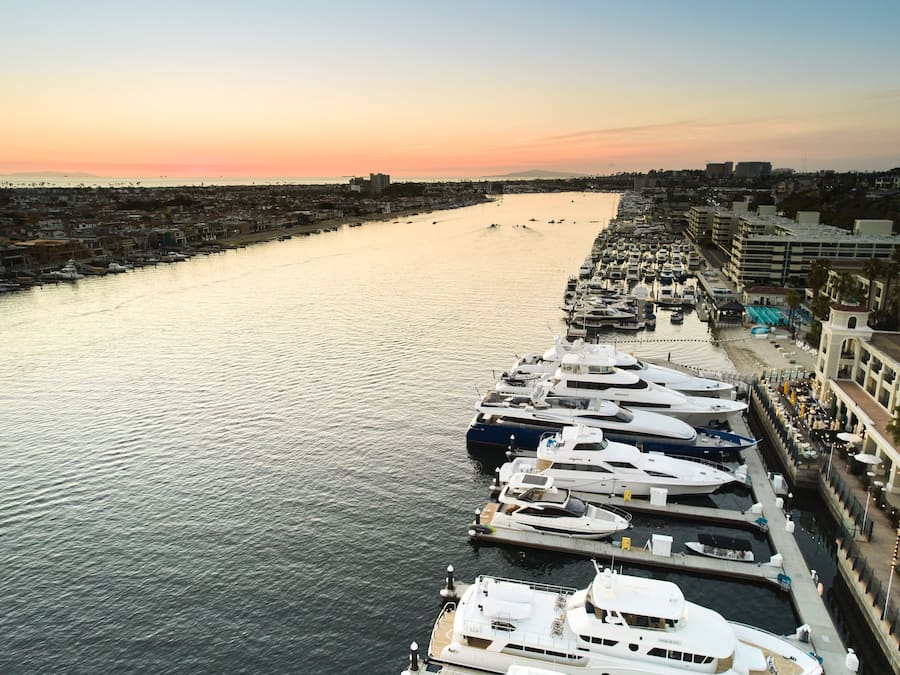 A marina with multiple yachts docked along a waterfront promenade.