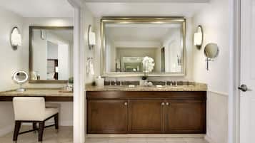 A bathroom with a large mirror, a vanity with a sink, a chair, and a cabinet.