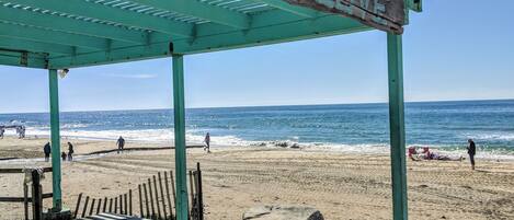 A beach pavilion with a sign reading "CRYSTAL COVE" and a picnic table.