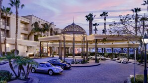 A hotel entrance with a covered pavilion, palm trees, and parked cars. - Balboa Bay Resort (Newport Beach)