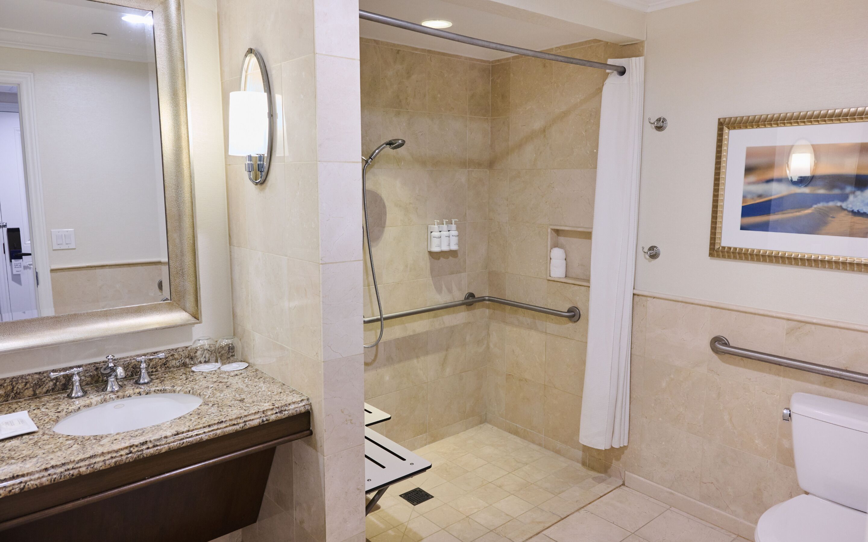 A bathroom with a granite countertop, a sink, a mirror, a shower with a glass door, and a toilet.