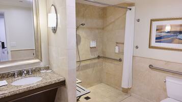 A bathroom with a granite countertop, a sink, a mirror, a shower with a glass door, and a toilet.