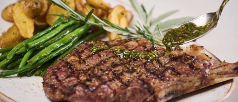 Une assiette comprenant un steak grillé, des haricots verts et des pommes de terre rôties.