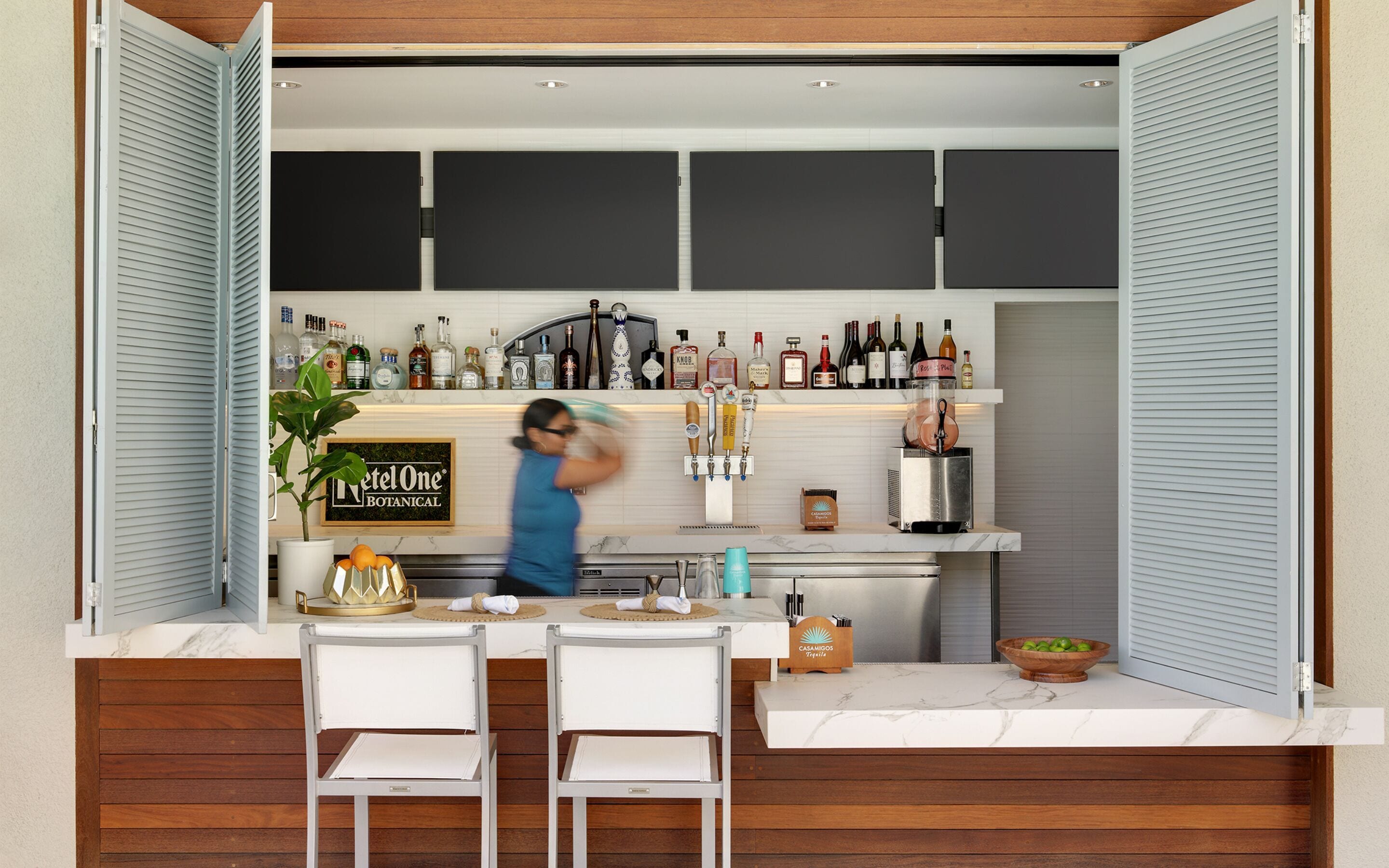 Une cuisine compacte équipée d’un mini-bar, d’un panneau indiquant la présence du mini-bar, et d’un coin bar avec des bouteilles et une machine à café.