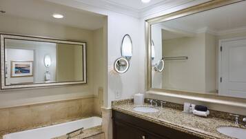 Une salle de bain avec un grand miroir, deux lavabos, une baignoire et un porte-serviettes.