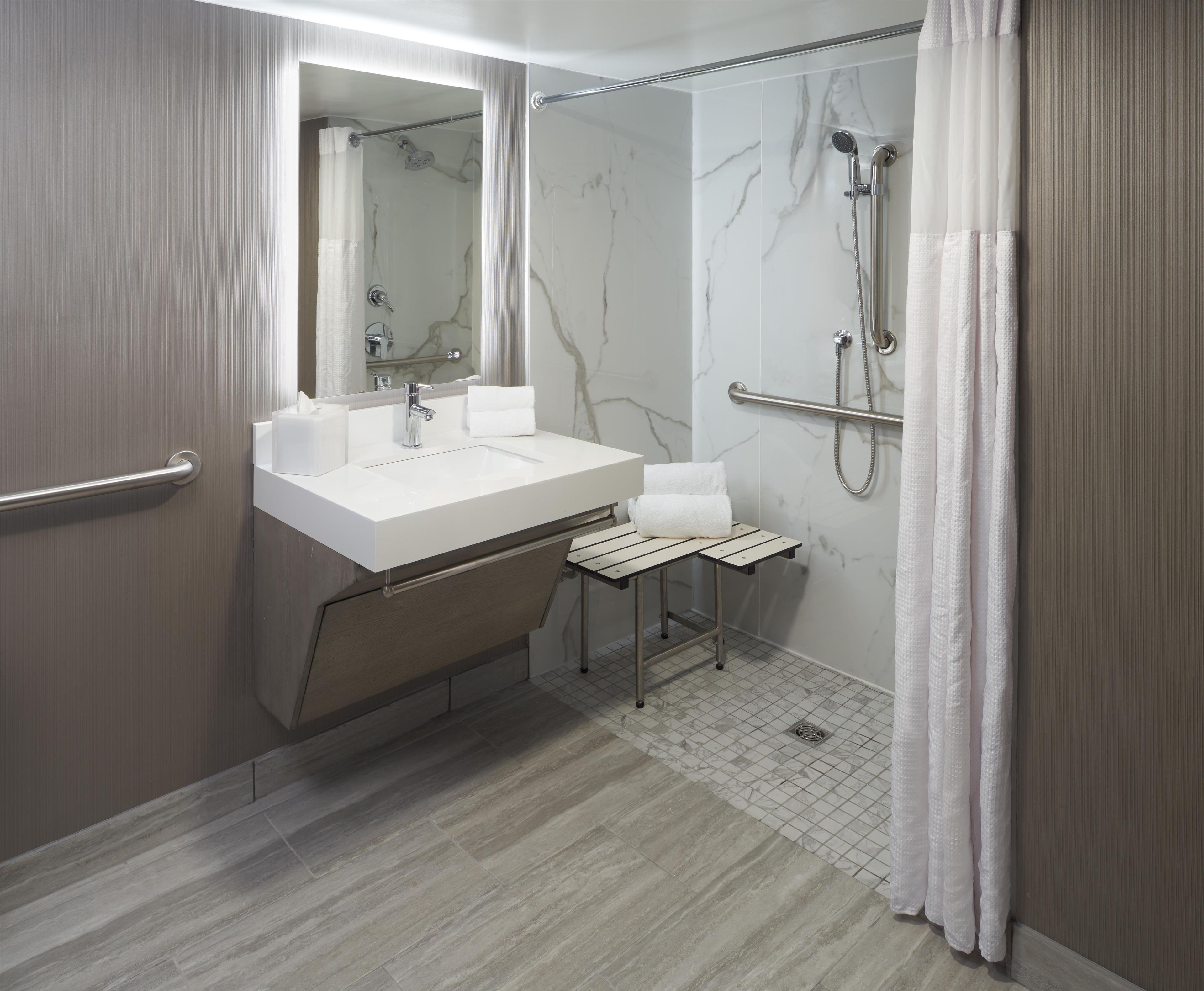 A modern bathroom with a marble shower, a sink with a towel rack, and a mirror.