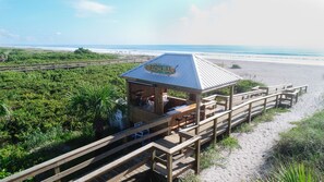 A beach bar with a wooden deck and a sign that reads "BEACH BAR". - Hilton Cocoa Beach Oceanfront (Cocoa Beach)
