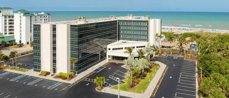 A modern hotel with a parking lot and a view of the beach.