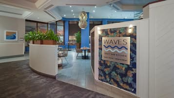 A reception area with a sign for 'WAVES Craft Bar Kitchen' and a seating area with tables and chairs.