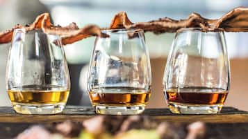 Three glasses of whiskey with a branch garnish on a wooden surface.