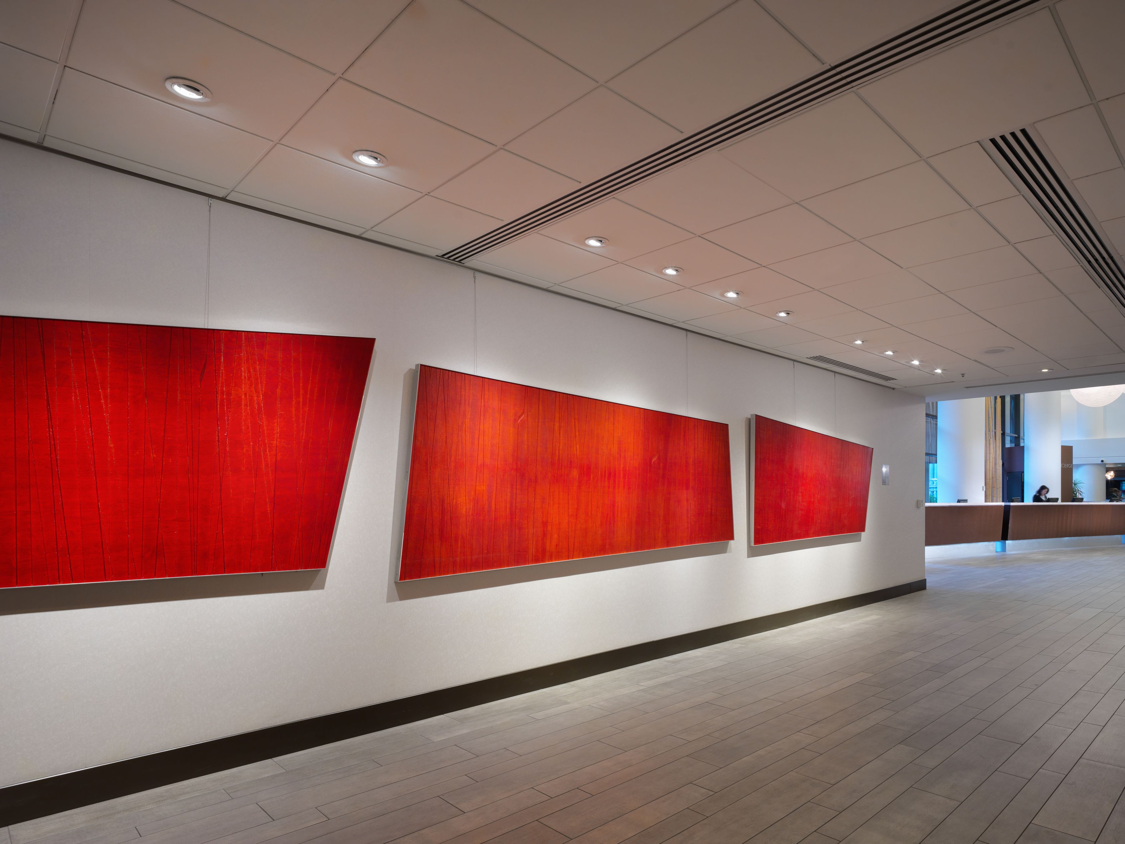 Un pasillo con tres paneles rojos grandes en la pared, un mostrador de recepción y un piso de baldosas.