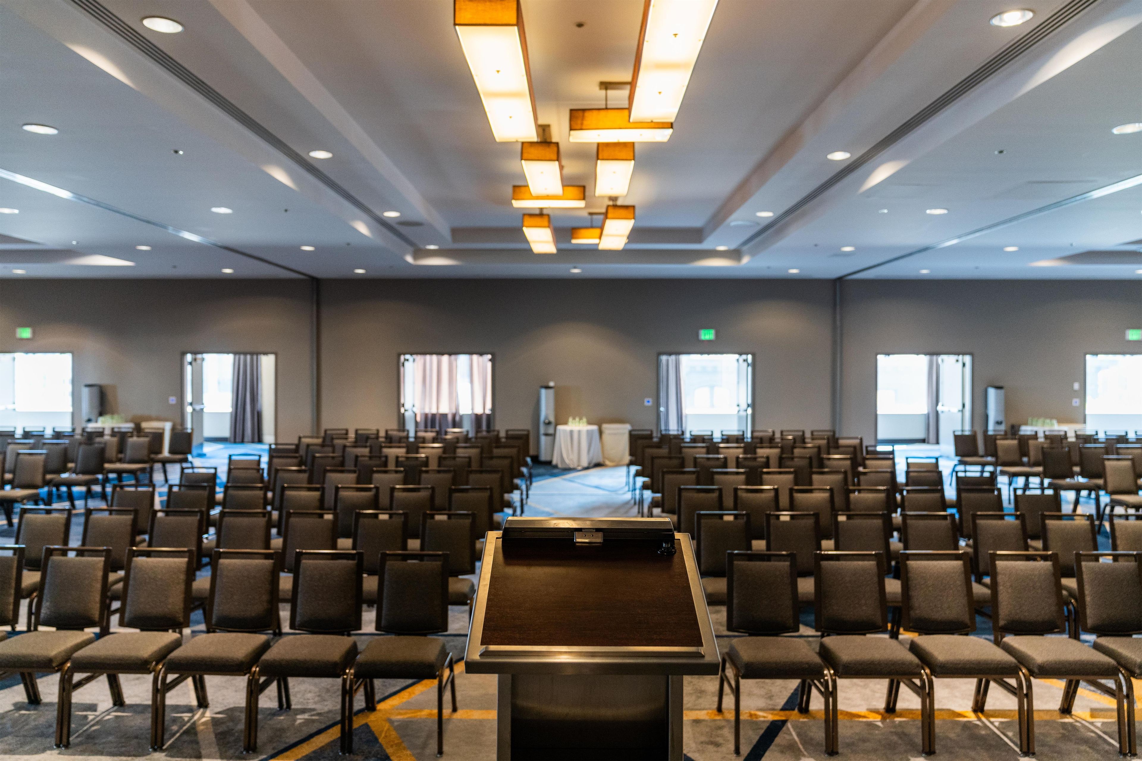 A conference room with rows of chairs, a podium, and a large table.