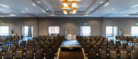 A conference room with rows of chairs, a podium, and a large table.