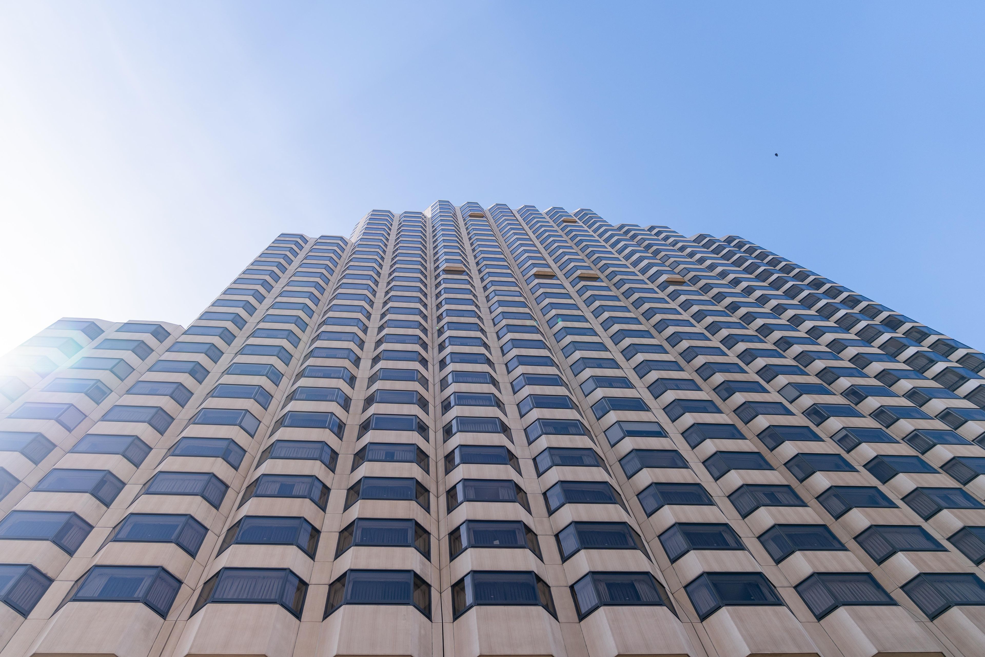 A tall, modern building with a repeating geometric facade and numerous windows.