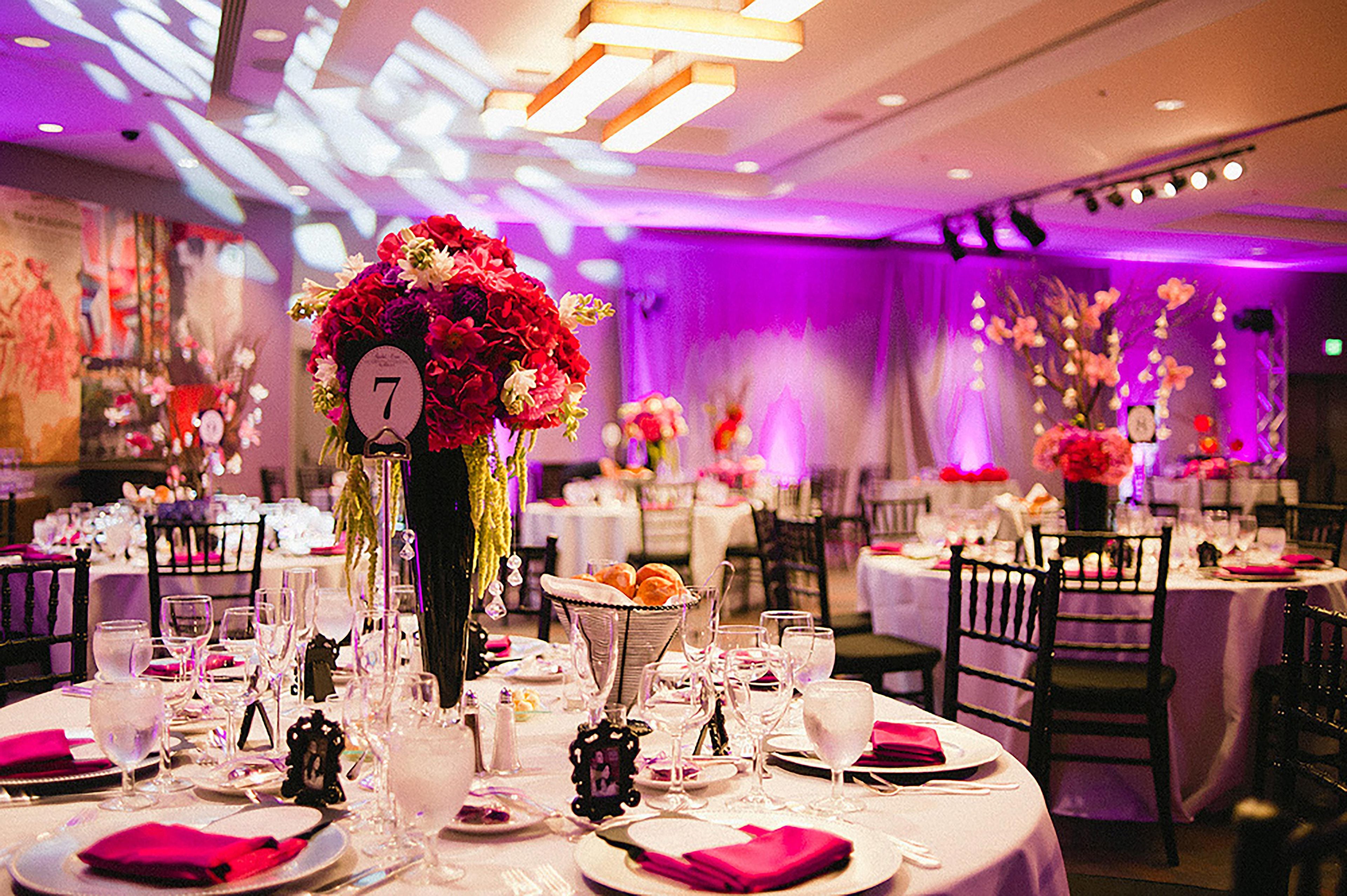 A banquet hall with round tables set for dining, each with a number placard, glasses, and cutlery.