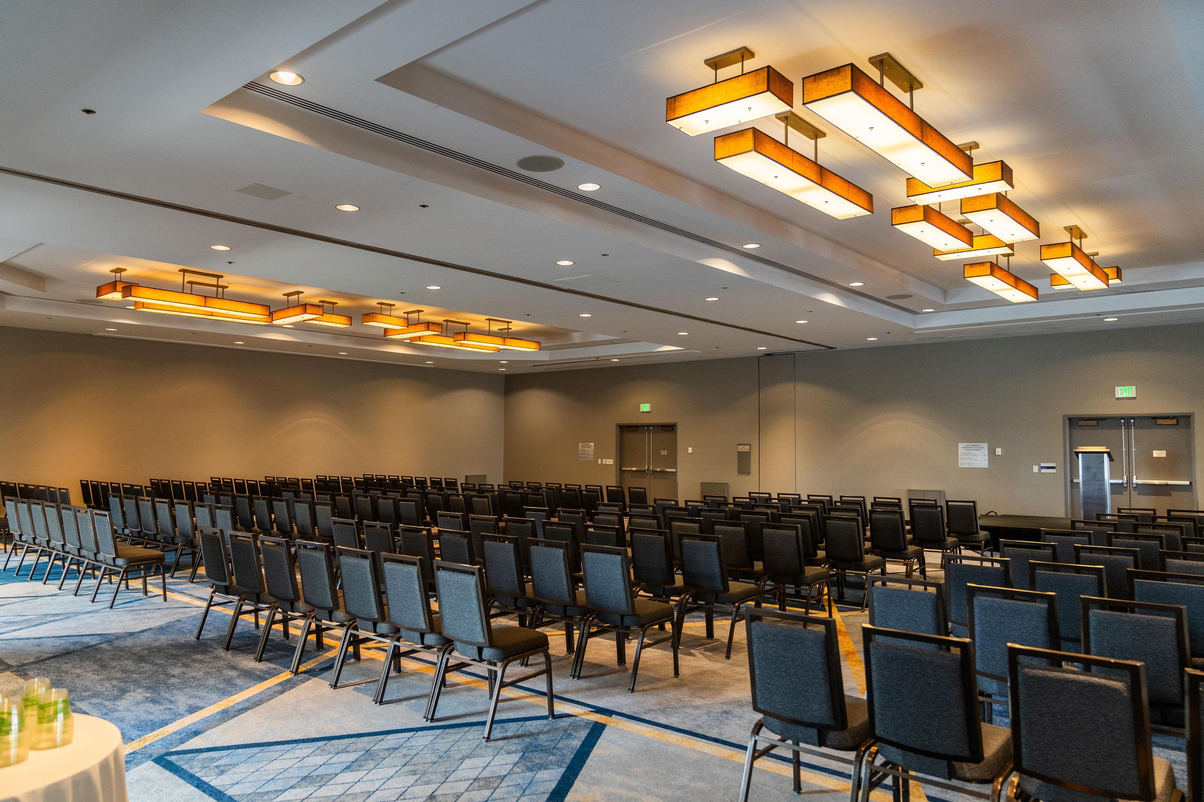 A conference room with rows of chairs, a stage, and modern lighting fixtures.