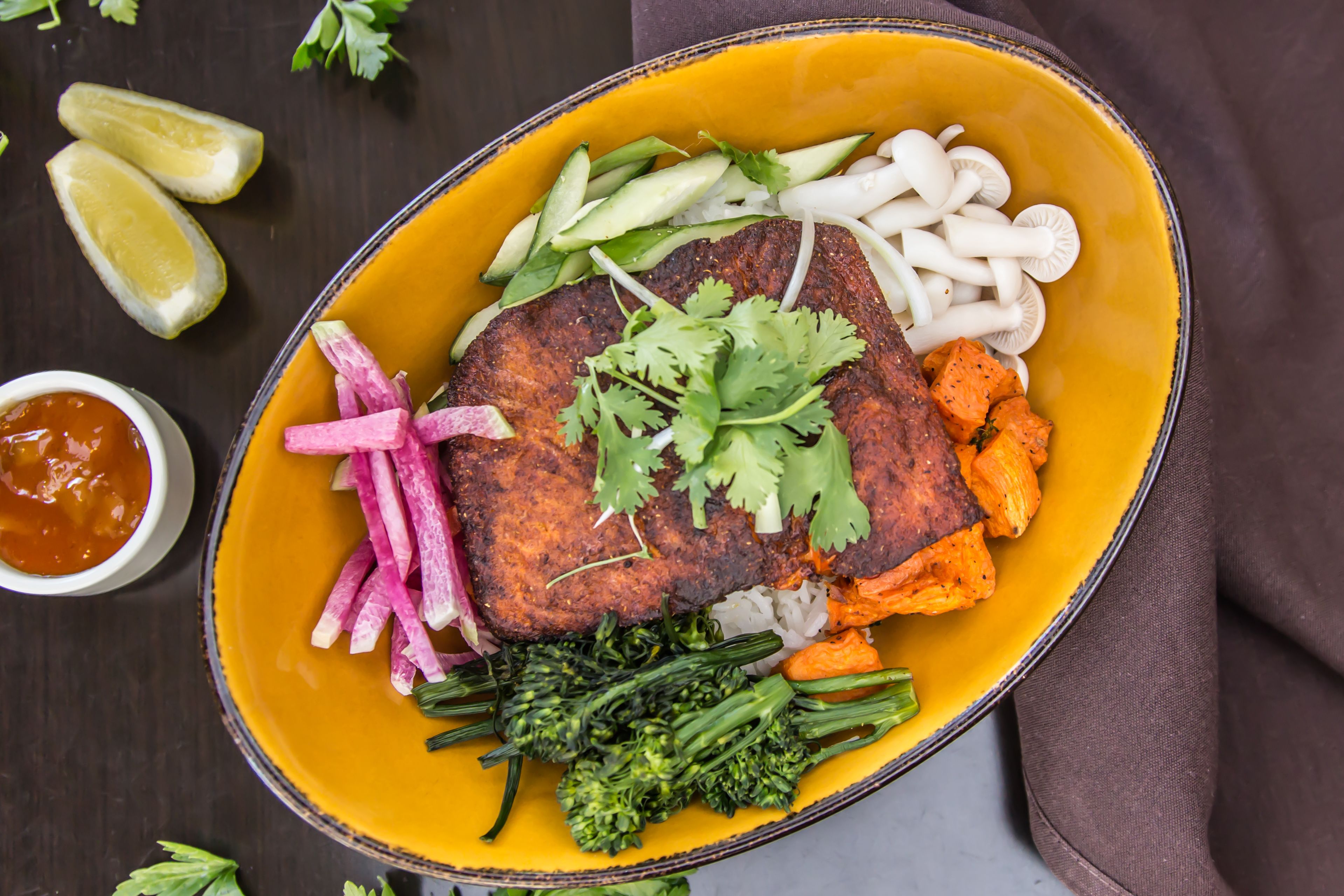 A meal with a steak, vegetables, and a side of rice in a yellow bowl.