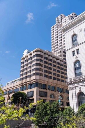 Un edificio a più piani con un design architettonico moderno, caratterizzato da un mix di linee curve e dritte, e un ingresso importante con un'ampia finestra ad arco.