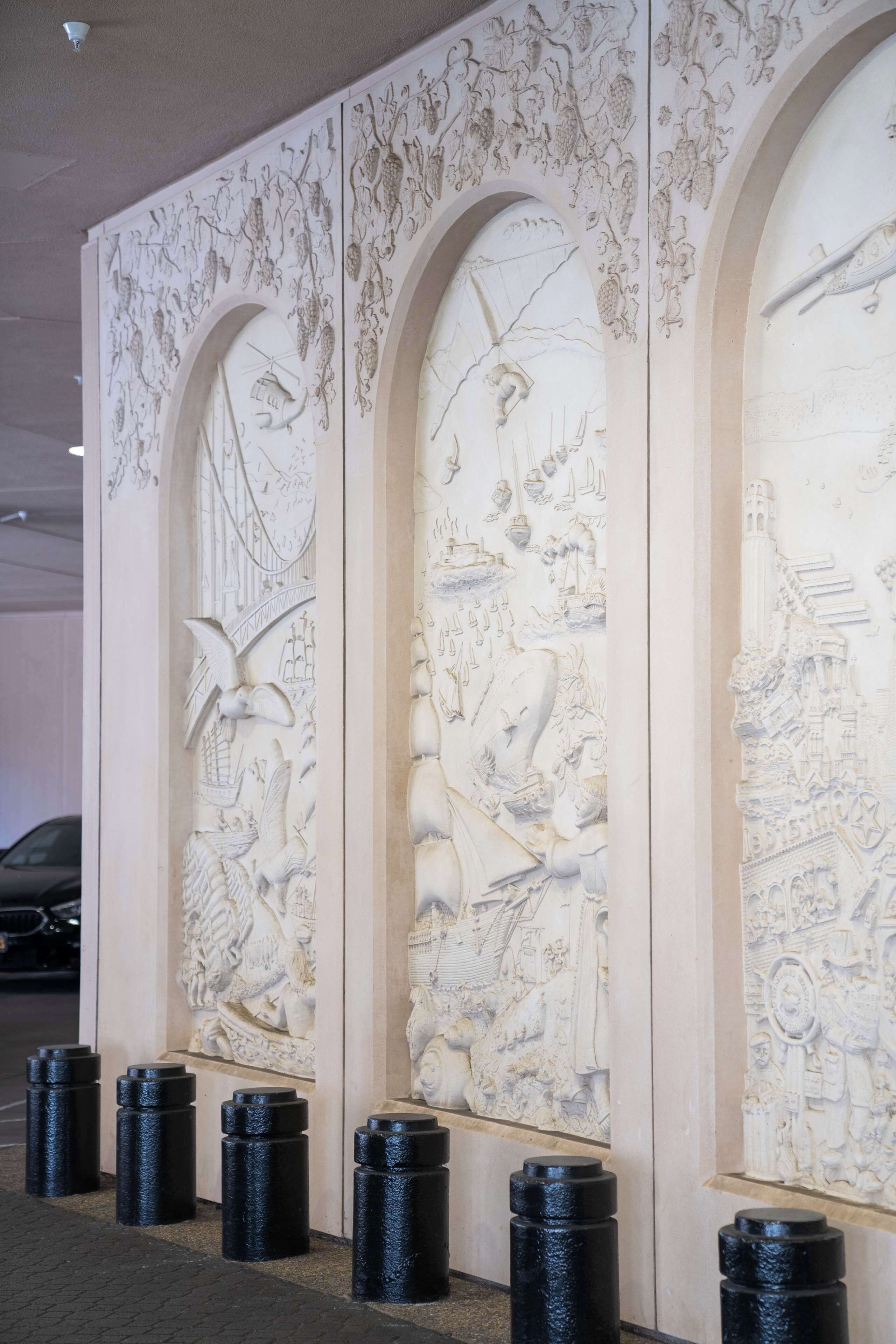 A wall with intricate carvings of various scenes and figures, likely part of a building's architecture.