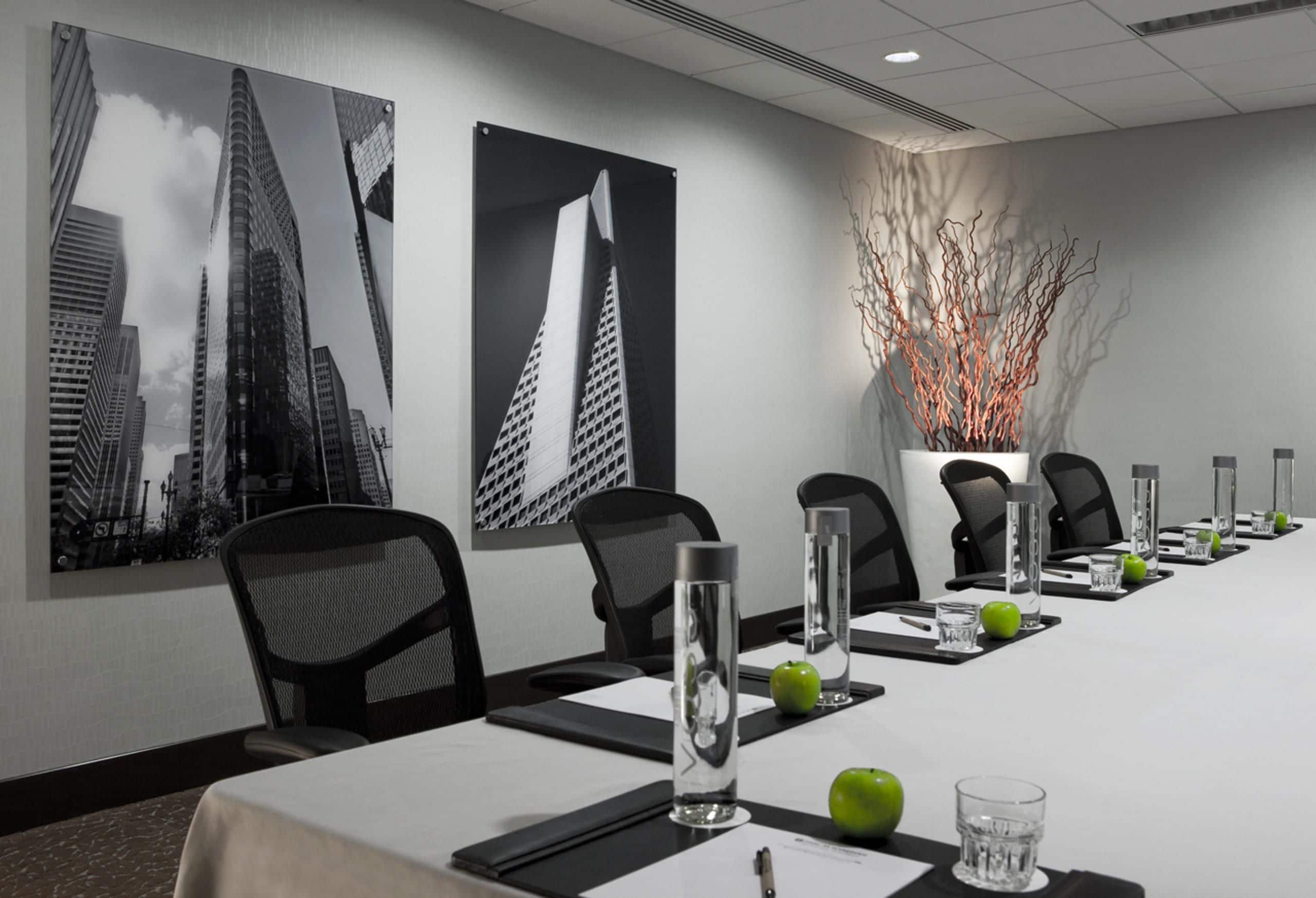 Een vergaderruimte met een lange tafel, stoelen, waterflesjes en appels.