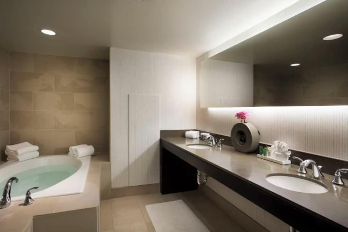 Un baño moderno con una bañera, dos lavamanos y un espejo grande.