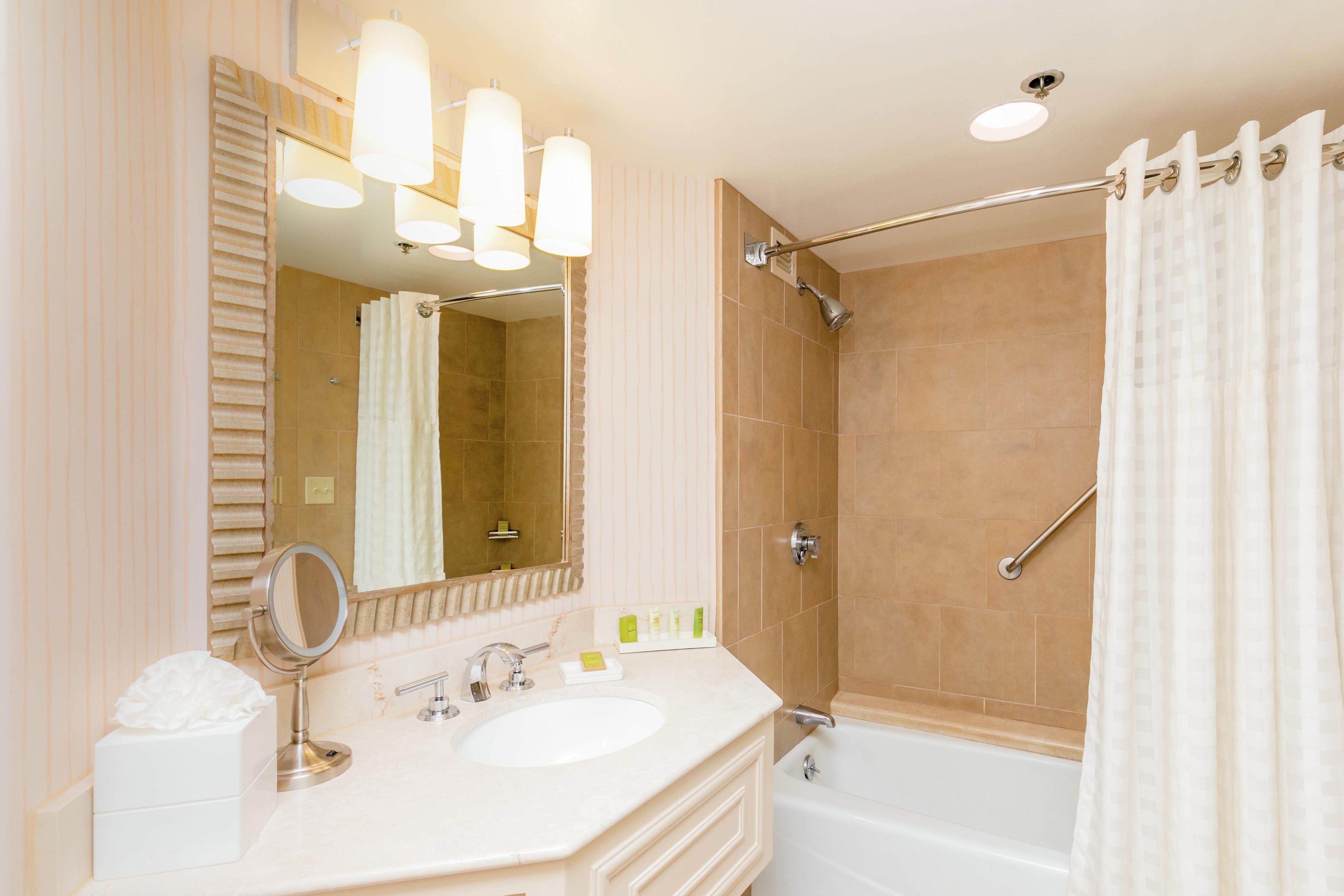 A bathroom with a sink, mirror, shower, and bathtub.