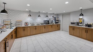 A modern kitchen with wooden cabinets, a white countertop, and a herringbone-patterned backsplash. - Best Western Greensboro Coliseum Inn (Greensboro)