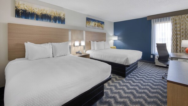 A hotel room with two beds, a desk, a chair, and artwork on the walls. - Best Western Greensboro Coliseum Inn (Greensboro)