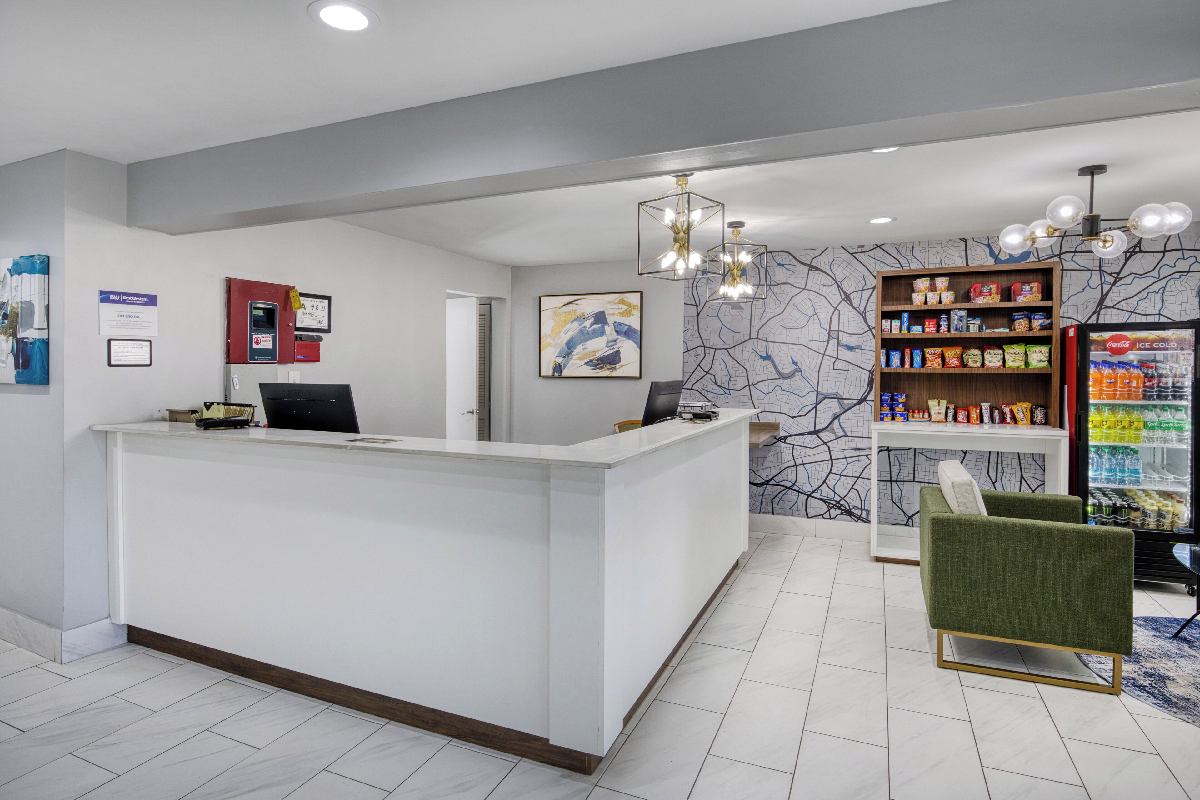 A reception area with a white reception desk, a map on the wall, a vending machine, and a green armchair.