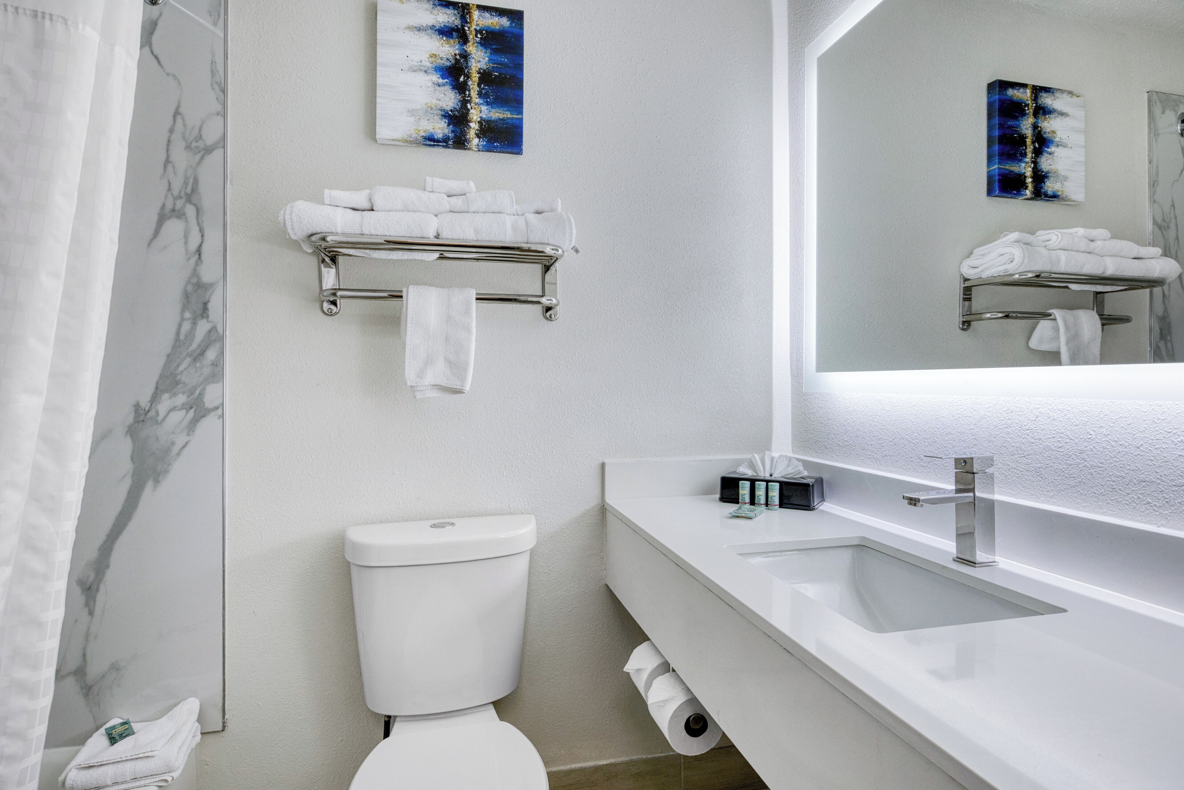 A modern bathroom with a toilet, sink, and towel rack.