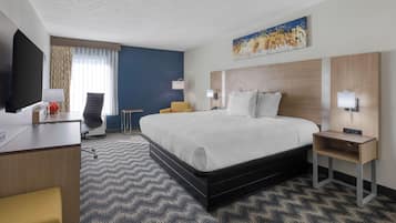 A hotel room with a bed, desk, chair, and a television.