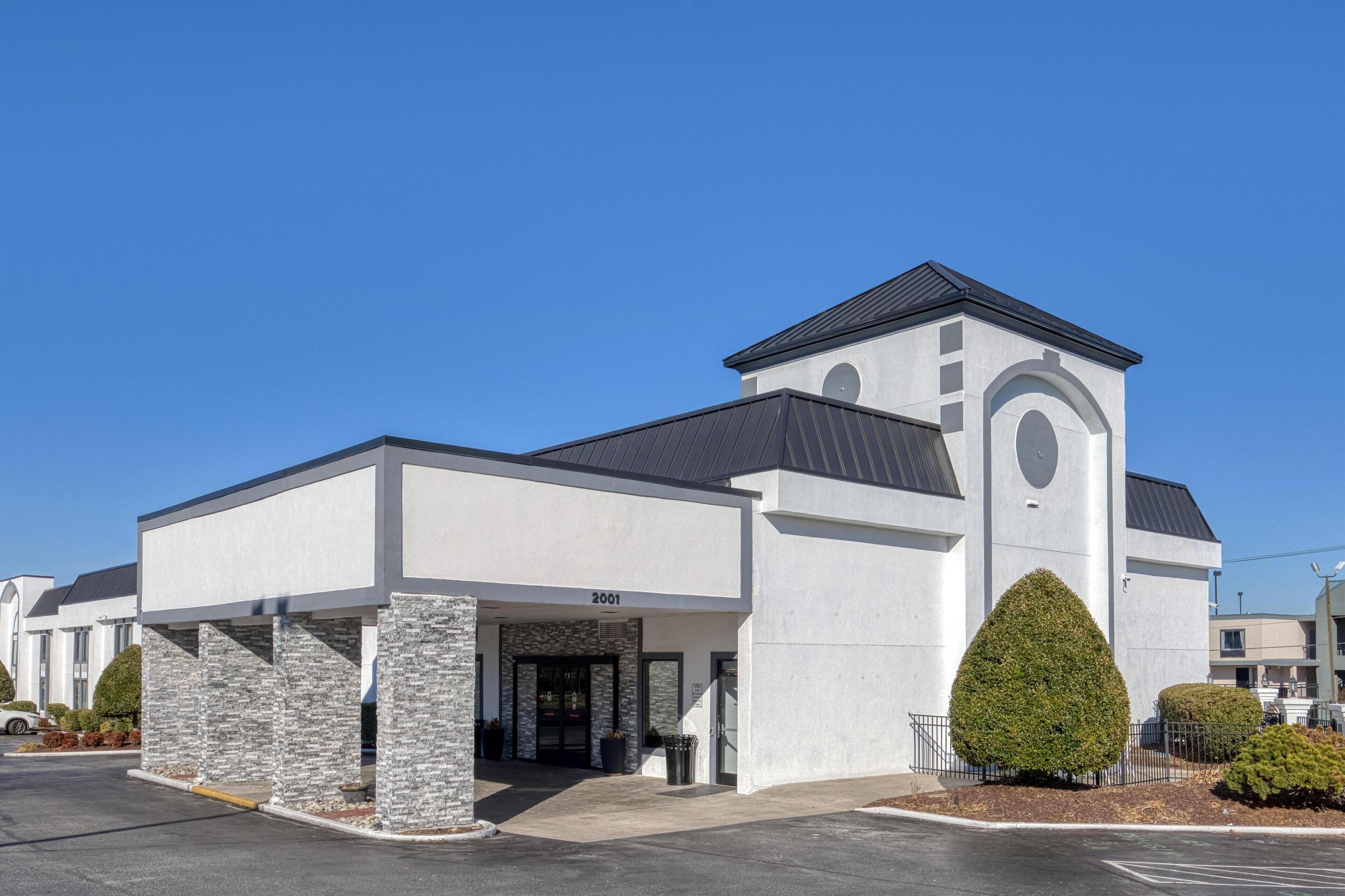 A modern building with a stone facade, a central entrance, and a small tower-like structure.